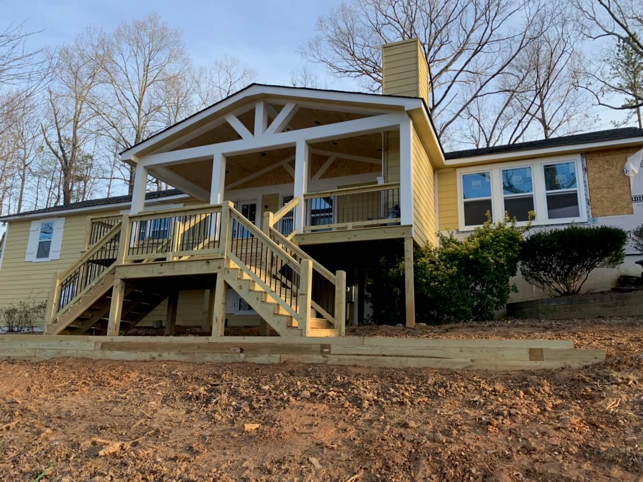 House with deck, stairs, and porch surrounded by trees