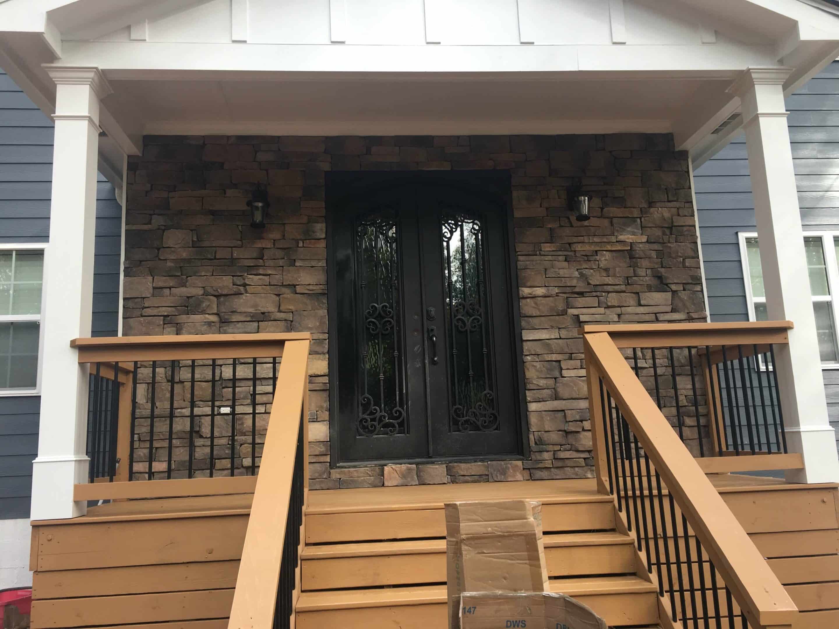 Front porch with wooden railing and welcoming black door